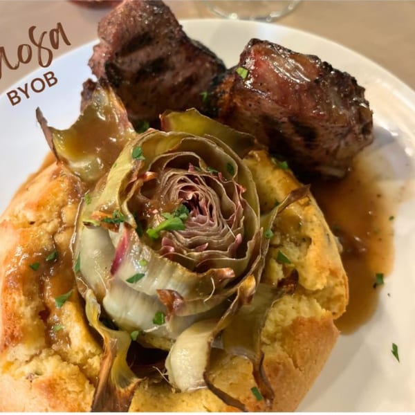 Grilled meat with an artichoke heart and a savory biscuit, drizzled with sauce.